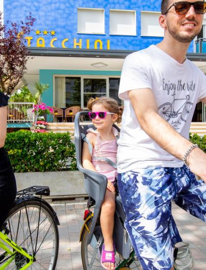 Famiglia in bici davanti a un hotel colorato.