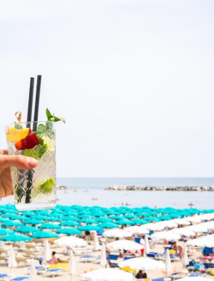 Cocktail in spiaggia con ombrelloni colorati e mare.