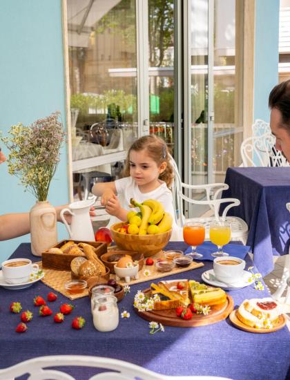 Famiglia fa colazione all'aperto con frutta e bevande.