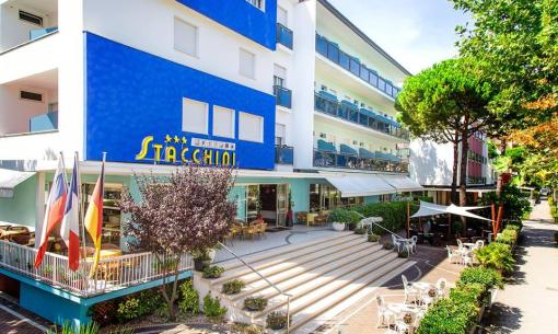 Hôtel moderne avec terrasse, drapeaux et sièges extérieurs.