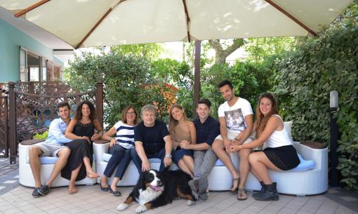 Group of smiling people sitting outdoors with a dog.