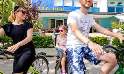 Famille à vélo devant un hôtel coloré.