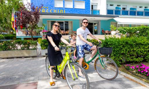 Family biking in front of a colorful hotel.