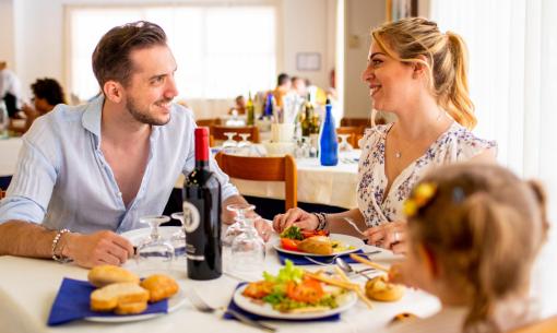 Happy family dining at a restaurant with wine and food.