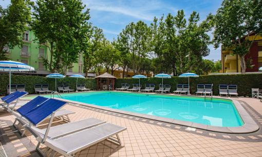 Outdoor pool with blue loungers and umbrellas.