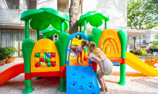 Child plays with mother on a colorful playground slide.