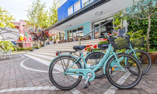 Biciclette davanti a un hotel colorato con bandiere e fiori.