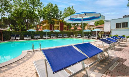 Piscine extérieure avec transats et parasols bleus.