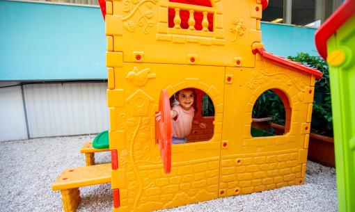 Enfant joue dans une maisonnette en plastique colorée dans la cour.