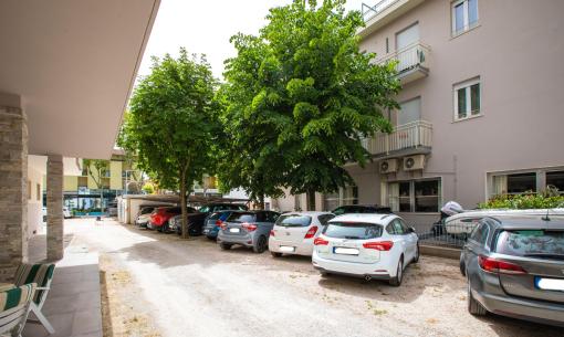 Parking lot with cars near a building and trees.