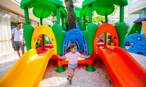 Bambina gioca su scivolo colorato in parco giochi.