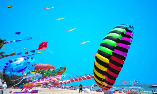 Festival di aquiloni colorati su una spiaggia soleggiata.