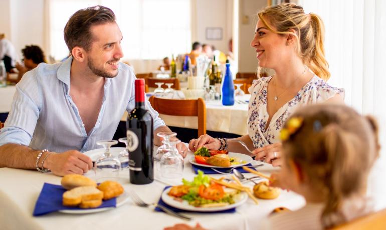 Happy family dining at a restaurant with wine and food.