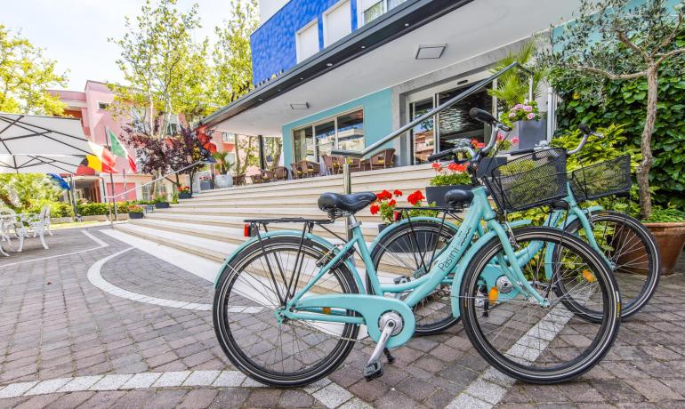 Biciclette davanti a un hotel colorato con bandiere e fiori.