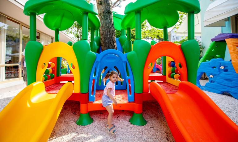 Bambina gioca su un colorato scivolo nel parco giochi.