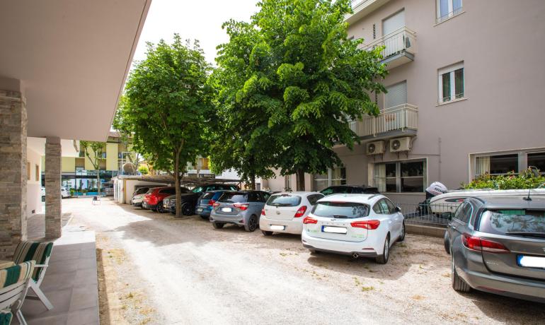 Parcheggio con auto vicino a un edificio e alberi.