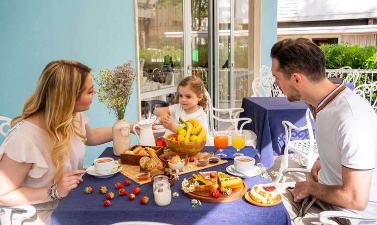 Famiglia fa colazione all'aperto con frutta e bevande.