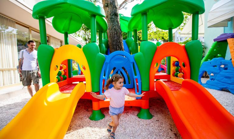 Bambina gioca su scivolo colorato in parco giochi.