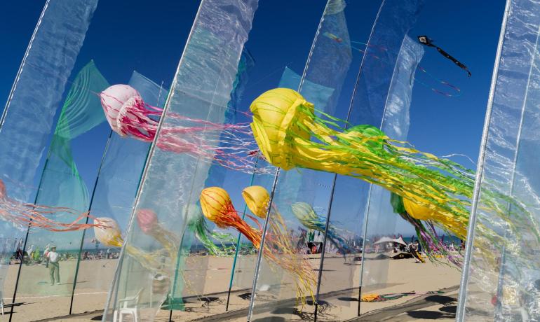 Jellyfish-shaped kites on a sunny beach.