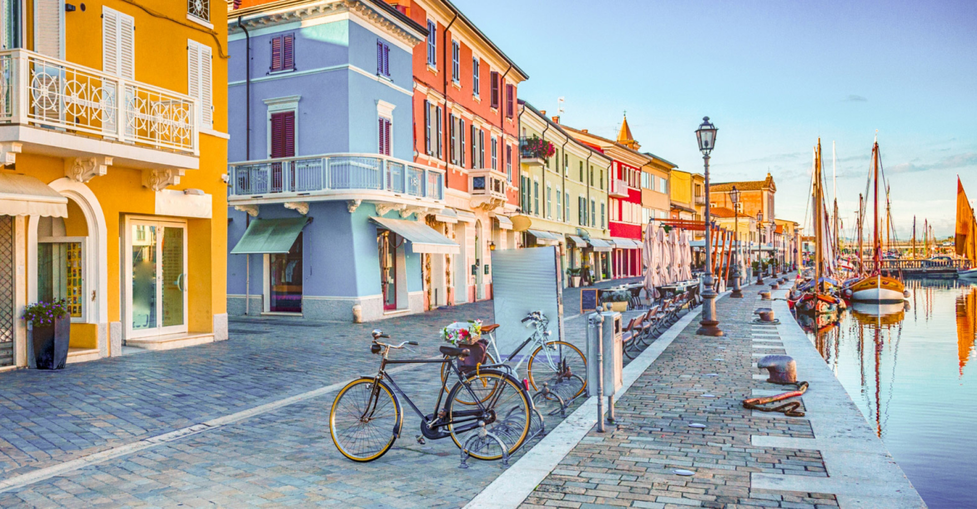 Strada colorata con biciclette e barche lungo un canale in una città pittoresca.