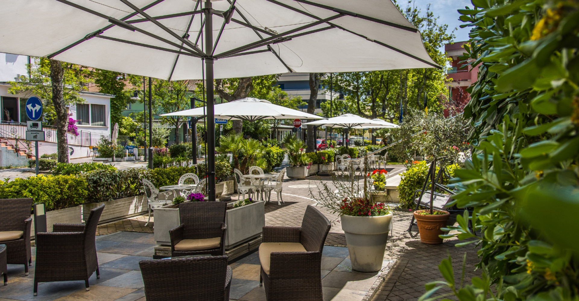 Giardino esterno con sedie, ombrelloni e piante, atmosfera rilassante e accogliente.