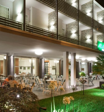 Ristorante moderno con terrazza all'aperto, illuminazione elegante e giardino curato.