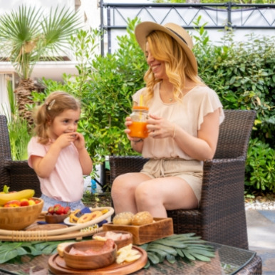 Madre e figlia gustano una colazione all'aperto con frutta e succhi freschi.