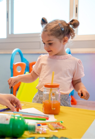 Bambina gioca con colori e succhi in una stanza colorata e luminosa.