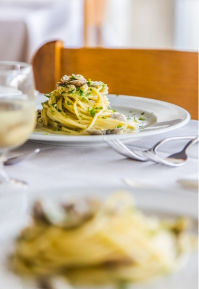 Piatto di spaghetti con vongole e prezzemolo, servito su tavola apparecchiata.