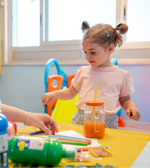 Bambina gioca con colori e succhi in una stanza colorata e luminosa.