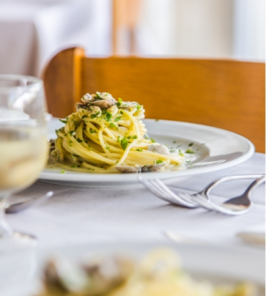 Piatto di spaghetti con vongole e prezzemolo, servito su tavola apparecchiata.