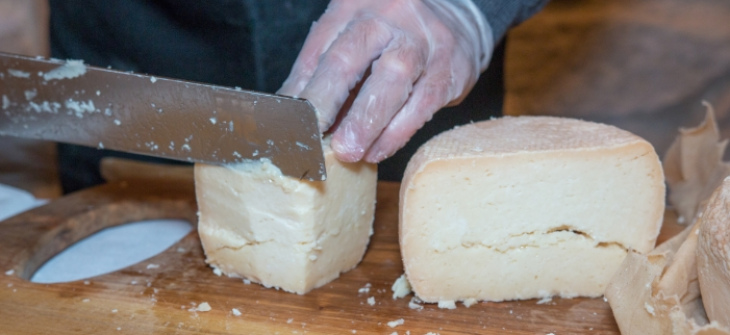 Taglio di formaggio stagionato su un tagliere di legno.