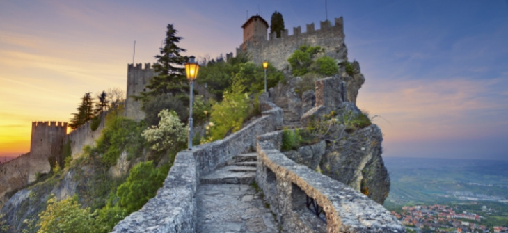 Castello su una roccia al tramonto, con vista panoramica sulla valle sottostante.