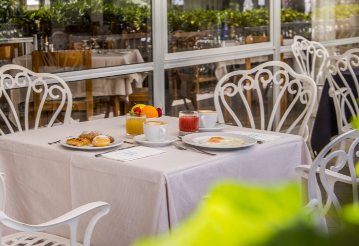 Colazione all'aperto con caffè, succo e dolci su tavolo elegante.