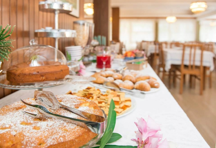 Buffet con dolci e pane in un ambiente elegante e luminoso.