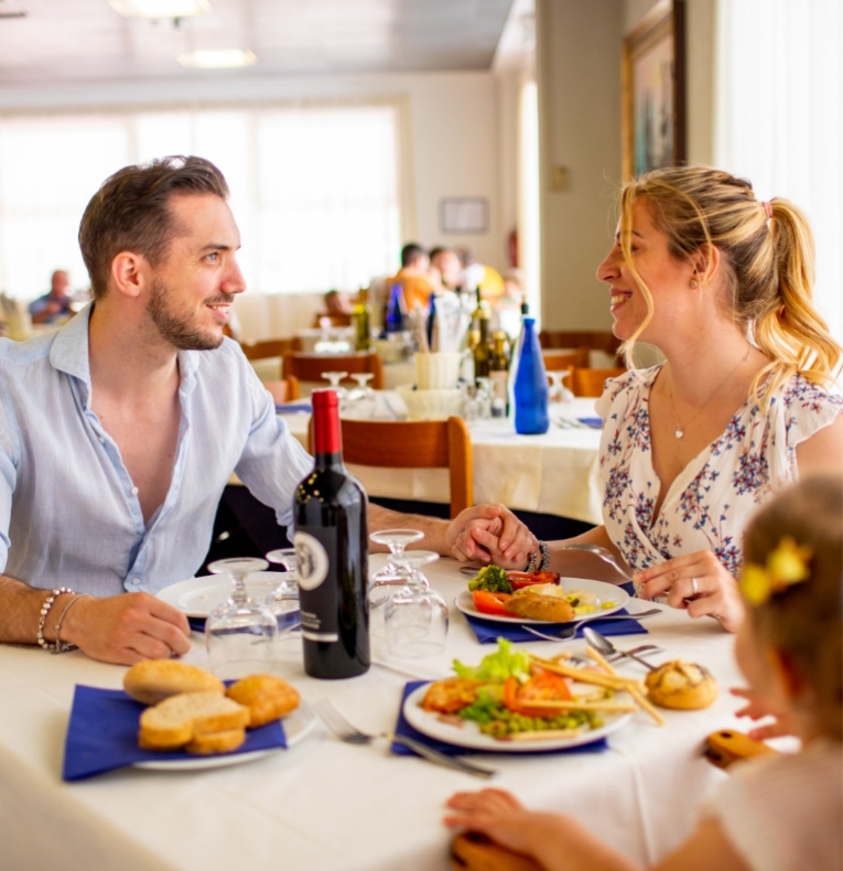 Coppia felice a cena con vino e piatti di verdure in un ristorante.