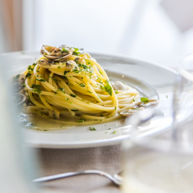 Spaghetti alle vongole con prezzemolo su piatto bianco, elegante e invitante.