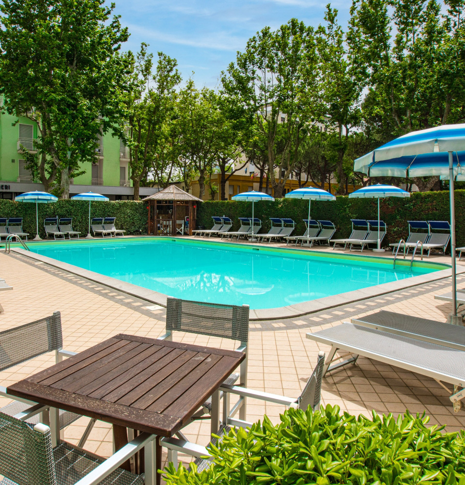 Piscina all'aperto con lettini e ombrelloni in un ambiente tranquillo.